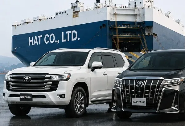 A HAT CO., LTD. car carrier at port with a Toyota Land Cruiser and Alphard ready for loading